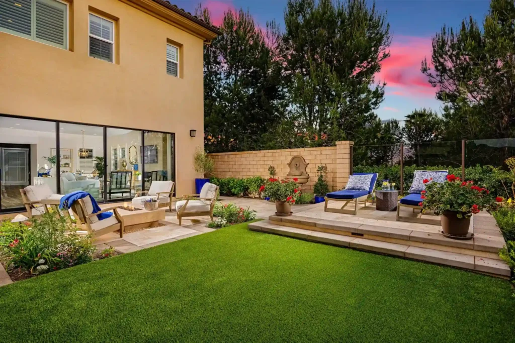 Landscaped backyard with lawn, fire pit, lounge seating, and garden patio.